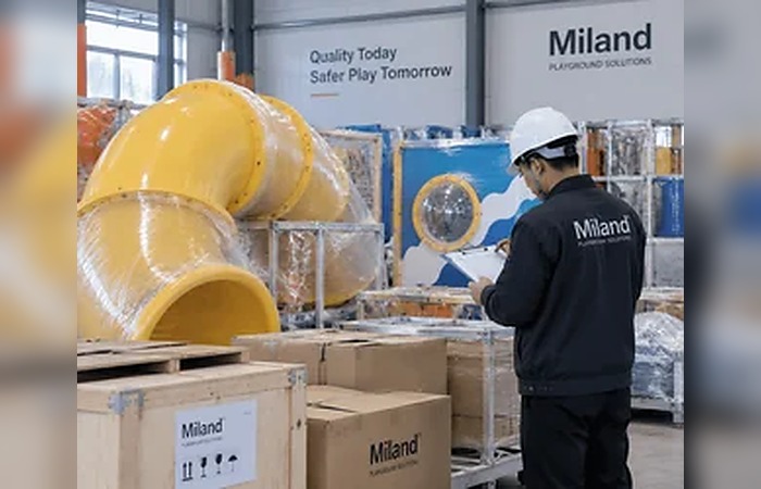 Специалист Miland проверяет игровое оборудование перед отправкой, рядом находятся упакованные трубы для горок и транспортные ящики